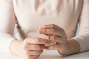 woman thinking about divorce pulling her ring off her finger.